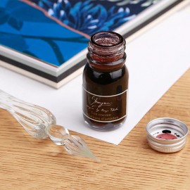 A set consisting of a glass pen and ink with flecks.